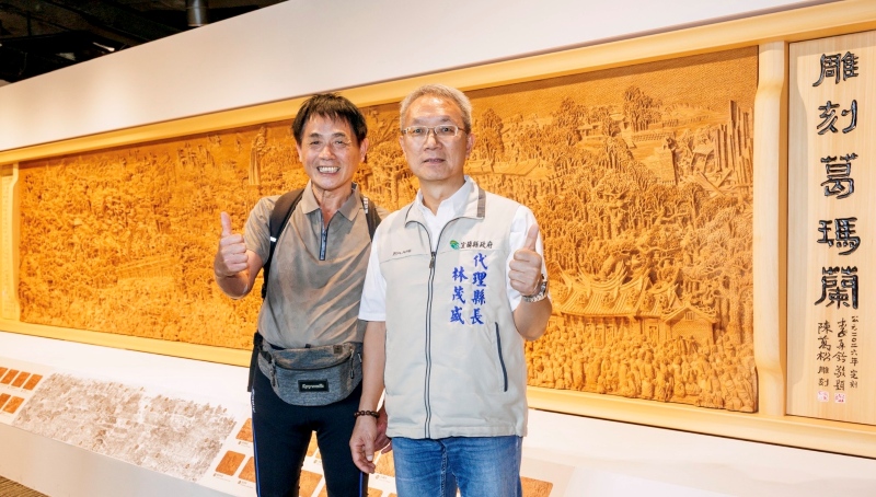 林茂盛代理縣長與藝術家陳萬松於巨型木雕作品「雕刻葛瑪蘭」前合影，讚嘆傳統工藝之美。
